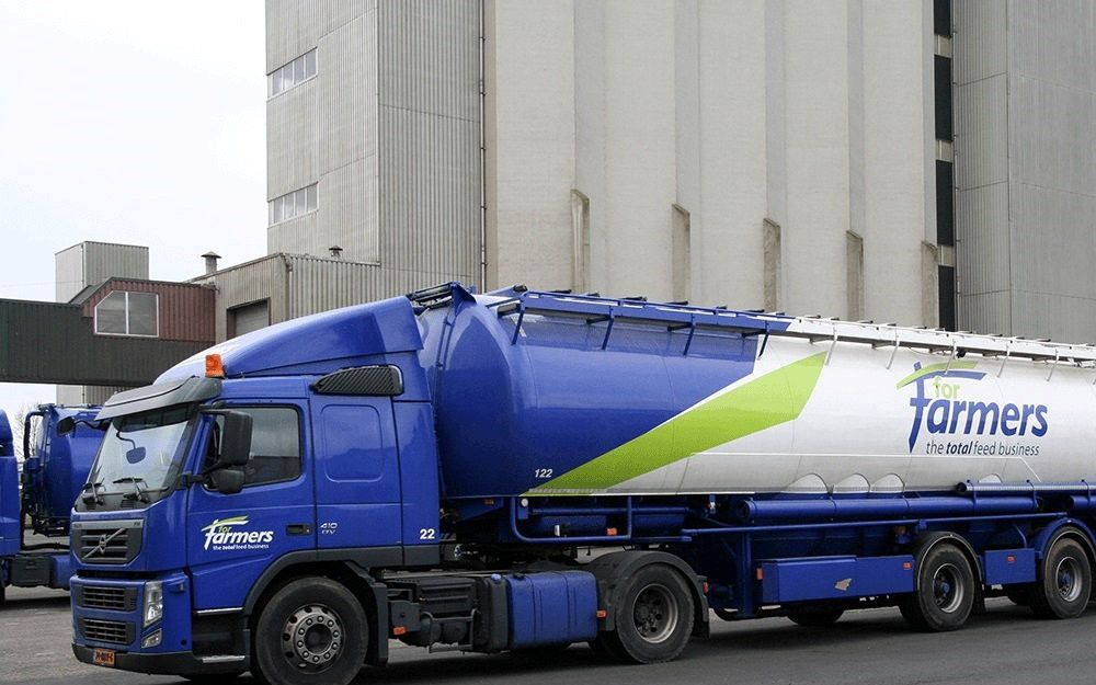 Een blauwe bulkwagen met de tekst ”For Farmers” staat voor een fabrieksgebouw.