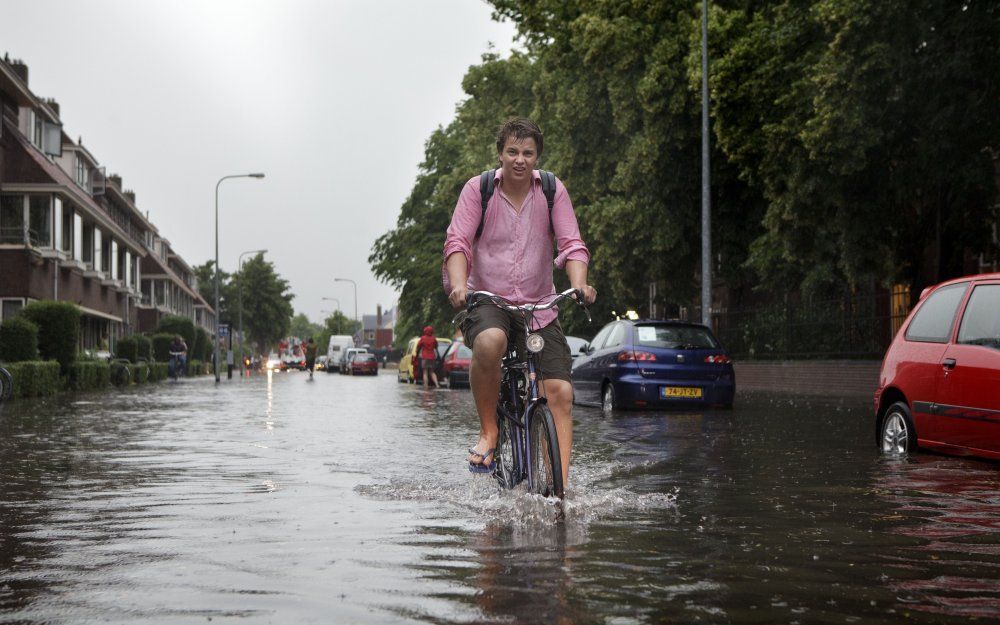 GRONINGEN - Een jongen fietst maandag door een ondergelopen straat in Groningen. Foto ANP