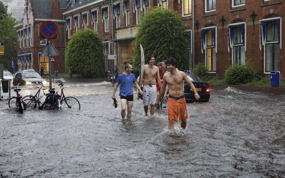 Jongens hebben maandag lol in een ondergelopen straat in Groningen. Foto ANP