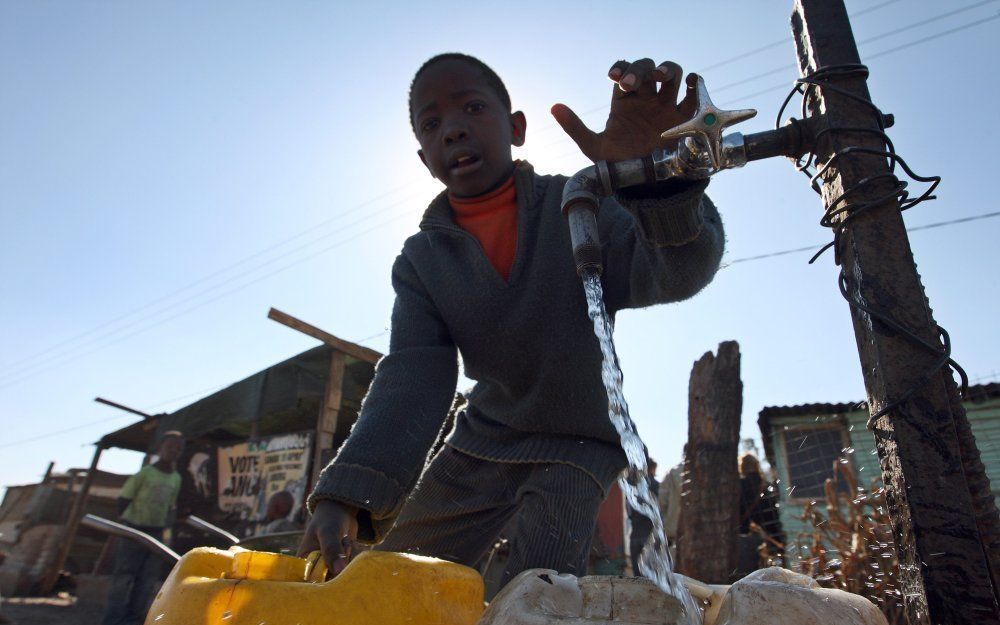 Een jongen tapt water in een vluchtelingenkamp ten oosten van Johannesburg. Foto EPA