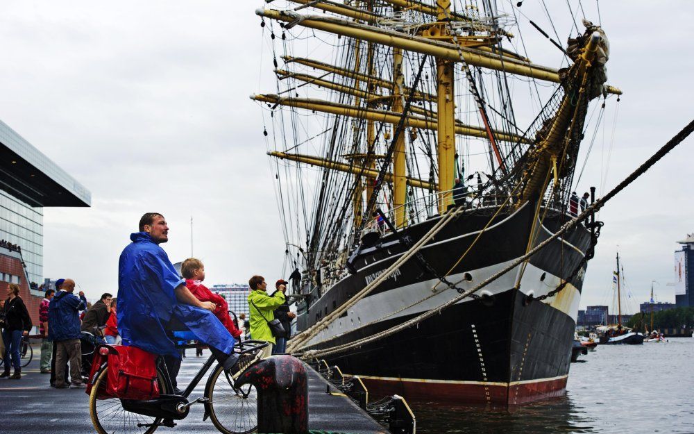 AMSTERDAM - Een vader met kind komen maandagochtend in de regen afscheid nemen van de Tal Ships in de haven van Amsterdam. Op andere plekken in Nederland zorgde de regen voor veel overlast. Foto ANP