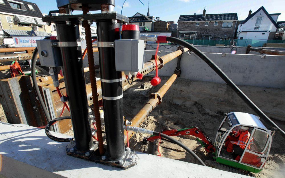 Terwijl hydraulische cilinders de kelderwanden naar beneden trekken, graven minikraantjes de grond uit de kelder weg. Foto MBS