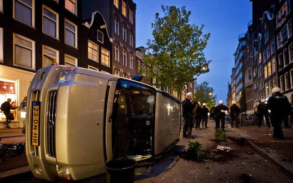 Een auto ligt op zijn kant na onlusten met krakers in Amsterdam. Foto ANP