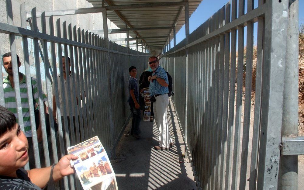 Een jongetje uit Bethlehem probeert ansichtkaarten te verkopen bij de militaire controlepost tussen Bethlehem en Jeruzalem. Foto Alfred Muller