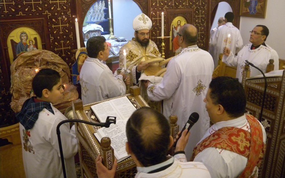 Priester Bishoy Kamel keurt de broden voor de Heilige Communie, terwijl een koor van diakenen zingend om hem heen staat. In de Koptische kerk in Utrecht waren gisteren zo'n 200 mensen bijeen voor de viering van het kerstfeest. Foto's RD