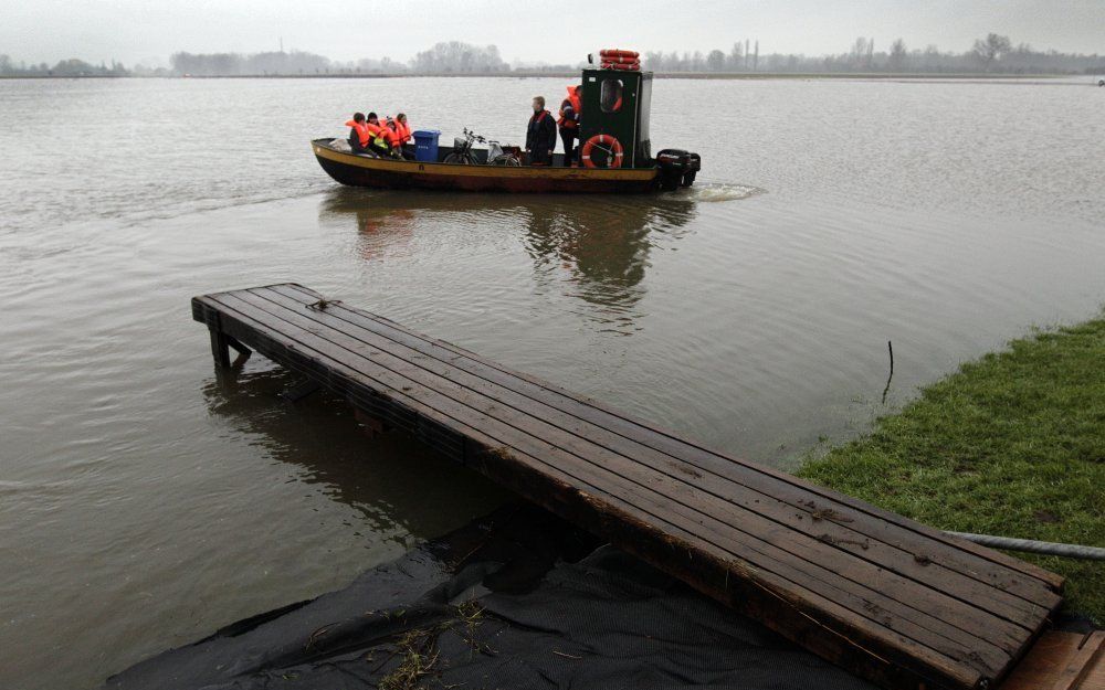 Inwoners van het buurtschap Fortmond worden woensdag per boot naar hun huizen gebracht. Fortmond is door het hoge waterpeil van de IJssel van de buitenwereld afgesloten. Foto ANP