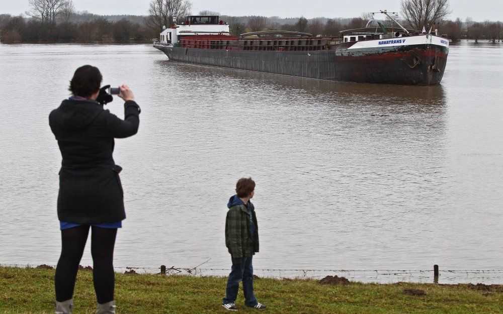 Belangstellenden kijken zaterdag naar het vastgelopen vrachtschip op de IJssel bij Zutphen. Het 90 meter lange schip liep vast toen het vanuit het Twentekanaal de IJssel wilde opvaren en een te wijde draai maakte. Foto ANP