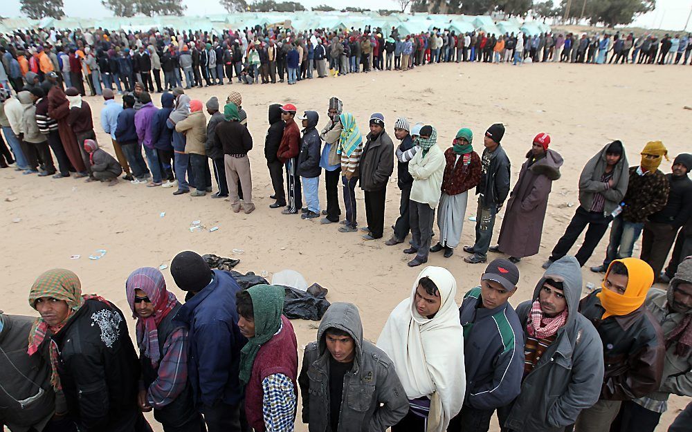 Vluchtelingen uit Libië wachten op voedsel van de UNHCR, net over de grens met Tunesië. Foto EPA