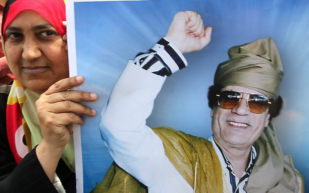 Een aanhanger van de Libische leider Gaddafi showt een poster van hem. Foto EPA