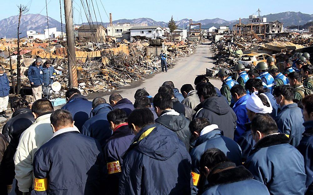 Japanse hulpverleners in gebed na het stoppen van zoek-en reddingsacties in Yamada. Foto EPA