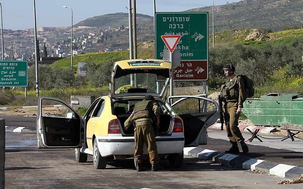 Israëlische soldaten doorzoeken een Palestijnse auto in de buurt van Nablus. Foto EPA