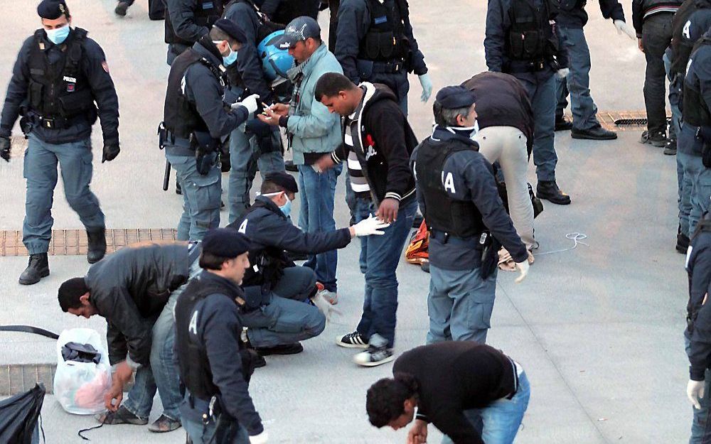 De Italiaanse politie controleert Afrikaanse vluchtelingen op Lampedusa. Foto EPA