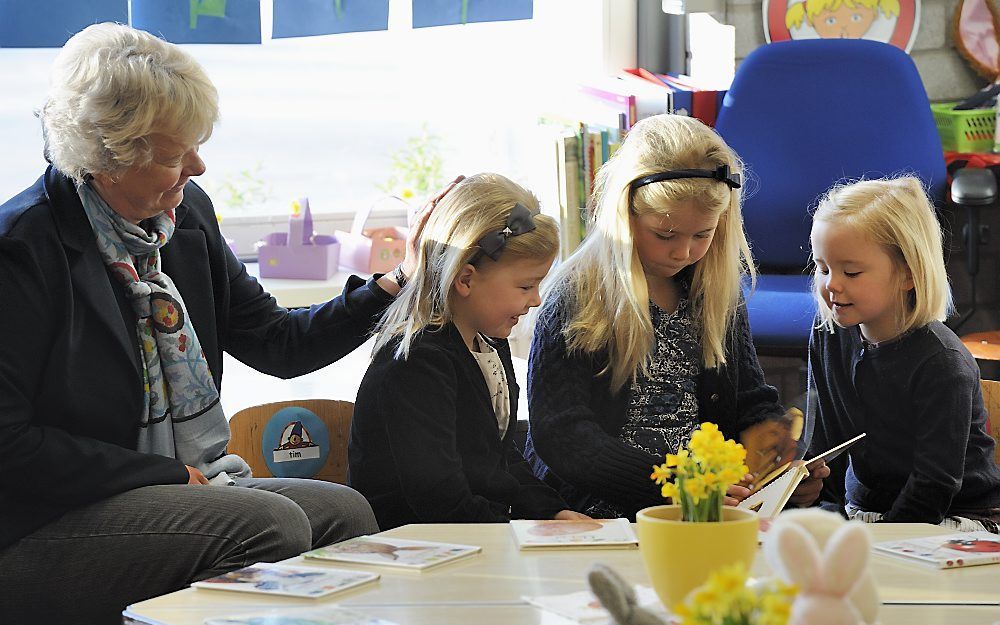 Prinses Ariane (R) kijkt met haar zusjes prinses Alexia (L) en prinses Amalia in een boekje op haar eerste dag op de basisschool. Links leerkracht Carla Buijs. Foto ANP