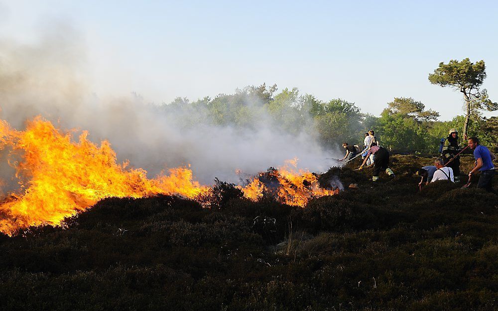 Brandweerlieden en vrijwilligers druk in de weer met het onder controle krijgen van de brand in het duingebied bij Schoorl. Foto ANP