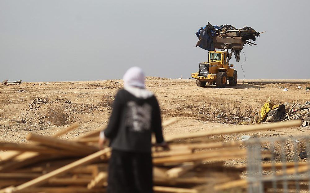 Bedoeïenenvrouw kijkt toe terwijl shovel in Negevwoestijn aan het werk is. Foto EPA