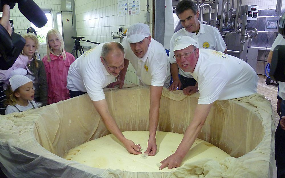 De vier kaasmakers (van links naar rechts) Gerard Korevaar, Wim van den Voet, Adrie Bikker en Johan Noordam leggen het kaasmerk op de grootste boerenkaas ooit.  Foto Ilona Noordam.