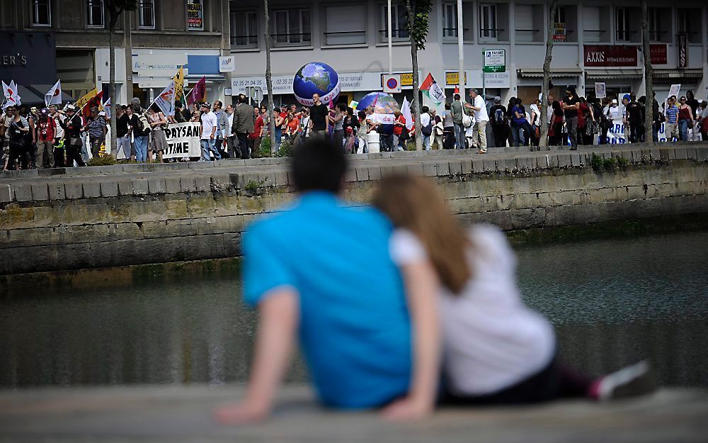 LE HAVRE – Een jong stel aanschouwde zaterdag een protestmars van demonstranten in Le Havre aan de vooravond van de G8-top, die donderdag begint in het Franse Deauville. Foto EPA