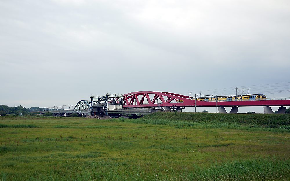 Een moderne dubbeldekstrein op een gloednieuwe spoorbrug. De rode brug neemt vanaf dinsdag de functie over van de spoorbrug tussen Zwolle en Hattem die stamt uit 1864, ten tijde van de Nederlandse industrialisatie. Foto Michiel Satink