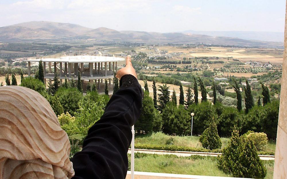 Een vrouw wijst naar de plaats in Syrië waar vorige week een massagraf is gevonden. Daarin zouden de lichamen van zeker tien politieagenten zijn begraven. Foto EPA