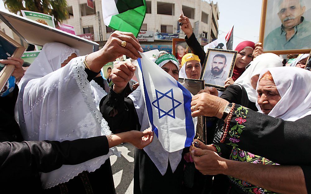 Palestijnse vrouwen proberen in het centrum van Hebron een Joodse vlag in brand te steken. De Palestijnen streven naar een eigen staat en stappen daarom naar de Verenigde Naties. Foto EPA