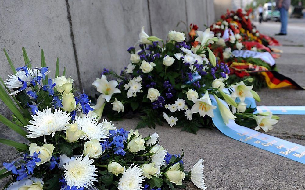 Om te herdenken dat vijftig jaar geleden met de bouw van de Muur begonnen werd hebben mensen bloemen gelegd. Foto EPA