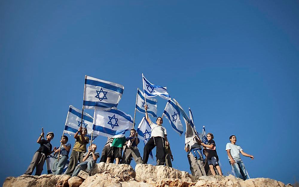 Joodse kinderen van kolonisten zwaaien met Israëlische vlaggen. Foto EPA