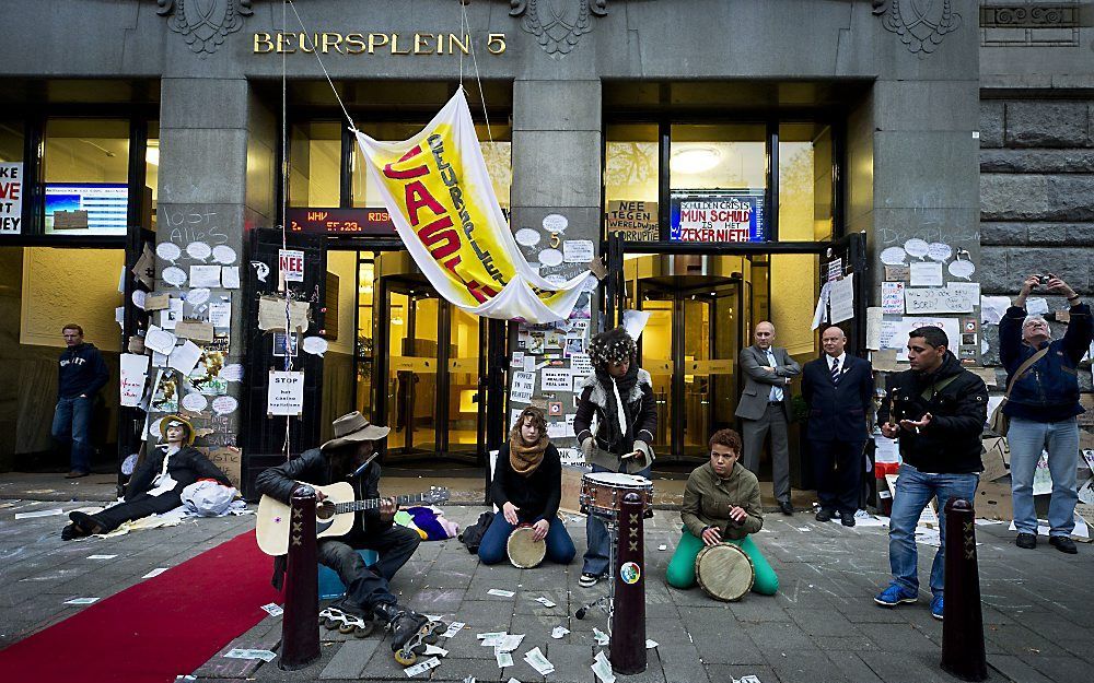 Voor de werknemers in het gebouw Beursplein 5 in Amsterdam lag maandagochtend de rode loper uitgerold. Actievoerders die deelnemen aan het Occupy-betoog heetten hen welkom met een erehaag en protestleuzen. Foto ANP