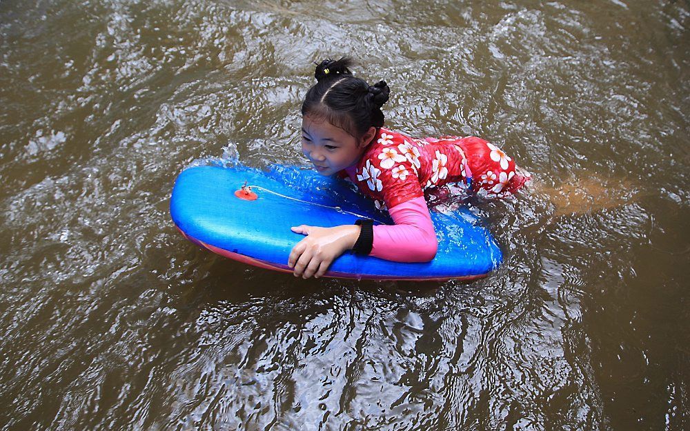 Meisje speelt in het water voor haar huis in Bangkok.  Foto EPA