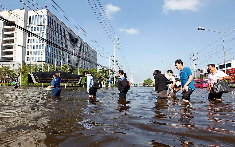 In de buitenwijken van Bangkok, rond de regeringsgebouwen waden bewoners door het water.  Foto EPA