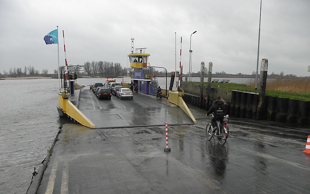 Scholieren fietsen de veerpont tussen Bergambacht en Groot-Ammers op. De veerstoep vertoont scheuren die momenteel worden gerepareerd. Foto RD