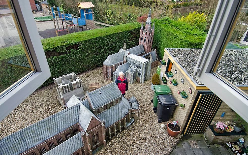 Chris van der Sman (76) tussen de kerken die hij de afgelopen vijftig jaar in zijn achtertuin bouwde. Links de Nieuwe Kerk van Delft, rechts de Oude Kerk, met de karakteristieke scheve toren. Naast de Nieuwe Kerk bouwt hij nu aan de Domtoren. Foto Frank v