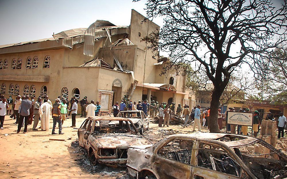 Uitgebrande auto's voor de St. Theresa, een rooms-katholieke kerk in een buitenwijk van Abuja. Foto EPA