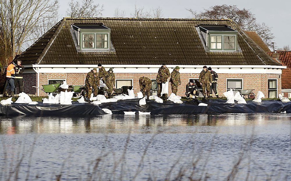 Militairen plaatsen zandzakken op de dijk van het Eemskanaal in het dorp Woltersum bij de stad Groningen. Foto ANP