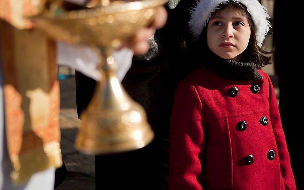 Een meisje kijkt naar een orthodoxe geestelijke op de Westelijke Jordaanoever in Israël. Foto EPA