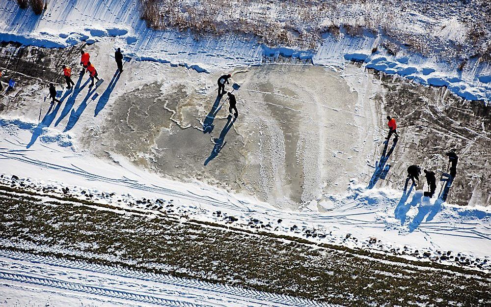 Vrijwilligers maken het ijs sneeuwvrij.  Foto ANP