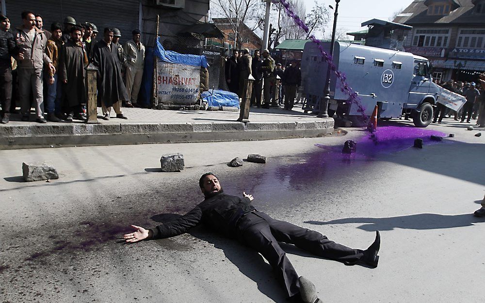 Een demonstrant ligt op straat terwijl de politie een waterkanon inzet. Srinagar, in de Indiase deelstaat Kashmir, was donderdag het toneel protest tegen nieuwe wetgeving over geneesmiddelen. Foto EPA