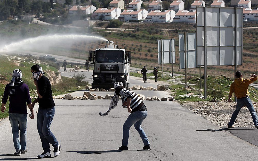 Palestijnse stenengooiende jongeren worden met een Israëlisch waterkanon weggejaagd.  Foto EPA