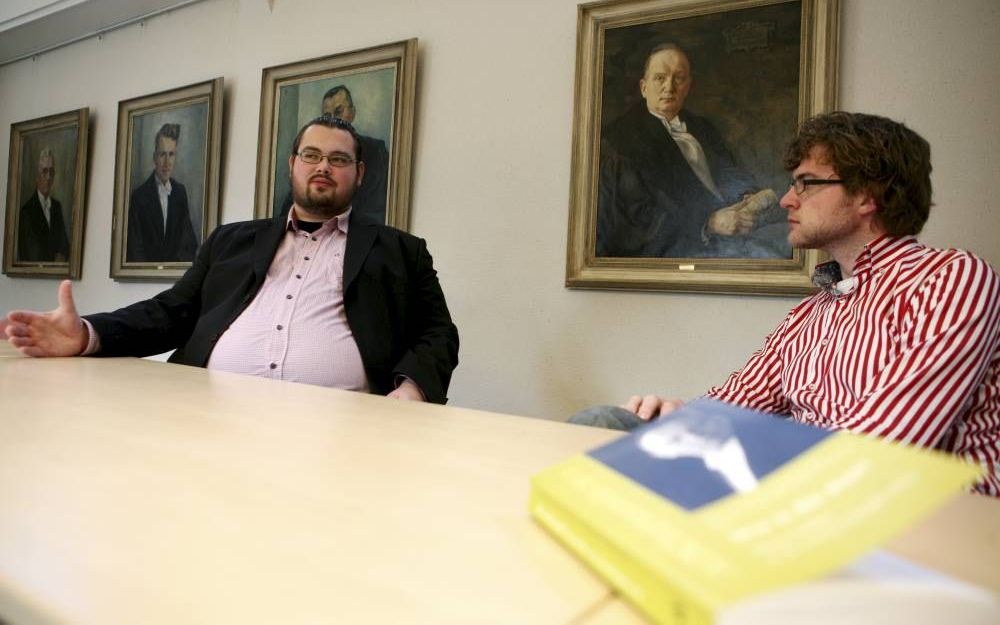 De Kamper studenten Marius van Rijswijk (l.) en Marinus de Jong zijn geboeid door de originaliteit van de vrijgemaakte voorman Klaas Schilder (te zien op het schilderij achter hen). Foto M. K. Boersema