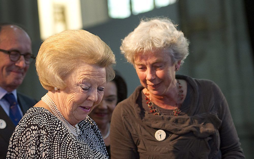 Koningin Beatrix krijgt een boek overhandigd door Nine Nooter, directeur Nationaal Comite 4 en 5 mei, tijdens de viering van het 25-jarig jubileum van het Comite in de Nieuwe Kerk in Amsterdam. Foto ANP