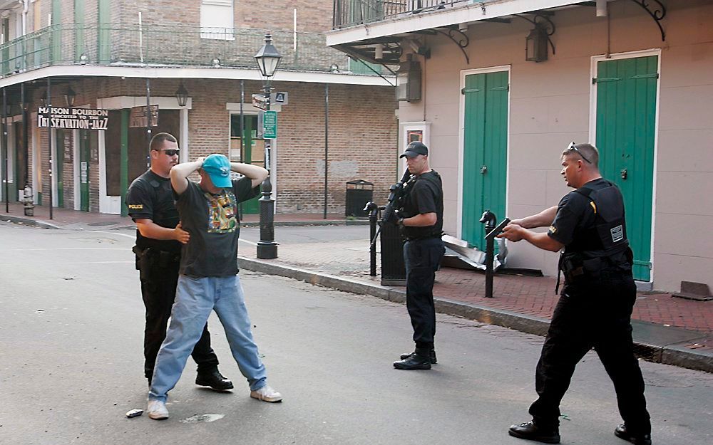 Politieagenten arresteren een inwoner van New Orleans die niet meewerkt aan de evacuatie tijdens orkaan Katrina. Foto EPA