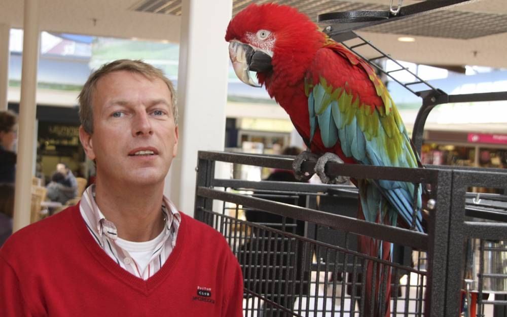 Juwelier Wim Smit met zijn papegaai Ara in winkelcentrum Maka­do in Alblasserdam. Foto Peter Stam