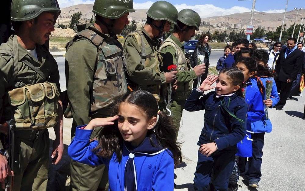 Syrische schoolkinderen delen bloemen uit aan militairen. Foto EPA