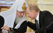 Wat zegt patriarch Kirill (l.) tegen premier Poetin (r.)? Betuigt hij zijn trouw aan het Kremlin? Of heeft hij ongezouten kritiek? De relatie tussen kerk en Kremlin is nauw, maar niemand weet er het fijne van. Foto AFP