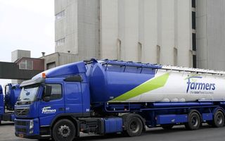 Een blauwe bulkwagen met de tekst For Farmers staat op asfalt voor een fabrieksgebouw.