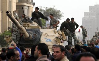 Egyptische soldaten kijken vanaf hun tank naar de demonstranten die hen omringen, zaterdag in het centrum van Cairo. Foto EPA