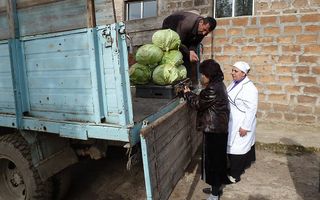 Voor de poort van de gaarkeuken in het Armeense Razdan stopt een vrachtwagen met kool. De kokkin en de domineesvrouw geven aan hoeveel kool er wordt ingekocht. Secuur wordt de groente op de laadbak gewogen.	 Foto Marie Verheij