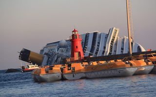 De Costa Concordia raakte een rif bij het eilandje Giglio, maakte slagzij en strandde uiteindelijk bij een strekdam. Foto EPA