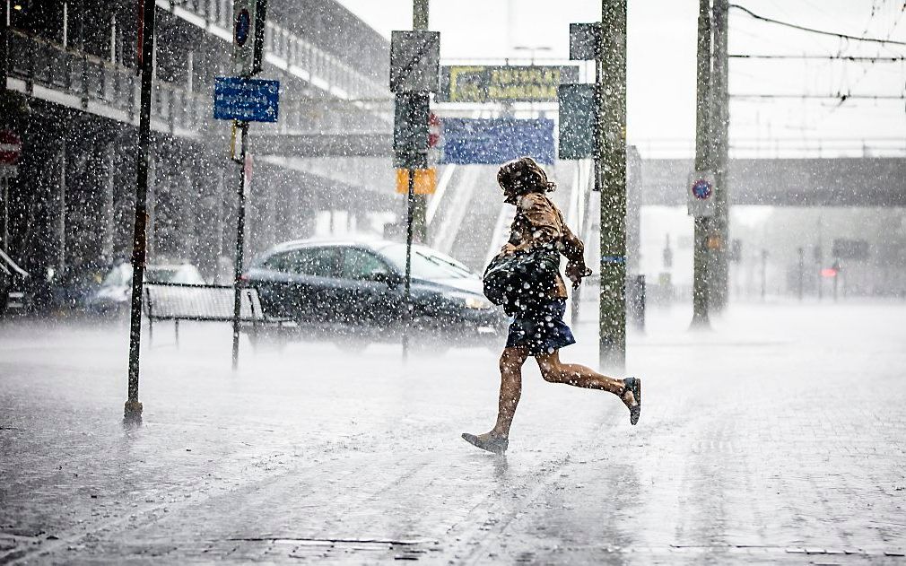 Een voorbijganger loopt door een stevige hoosbui in het centrum van Den Haag. beeld ANP