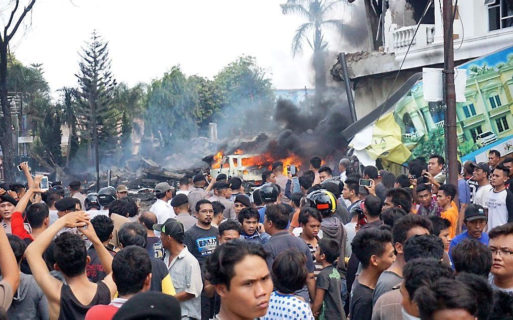 Omstanders bekijken de ravage na de crash van een militair toestel in Medan. Beeld AFP