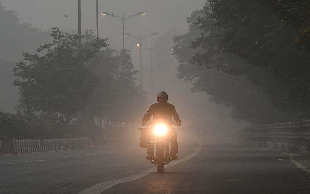 Een motorrijder rijdt door de smog in New Delhi, India. beeld EPA